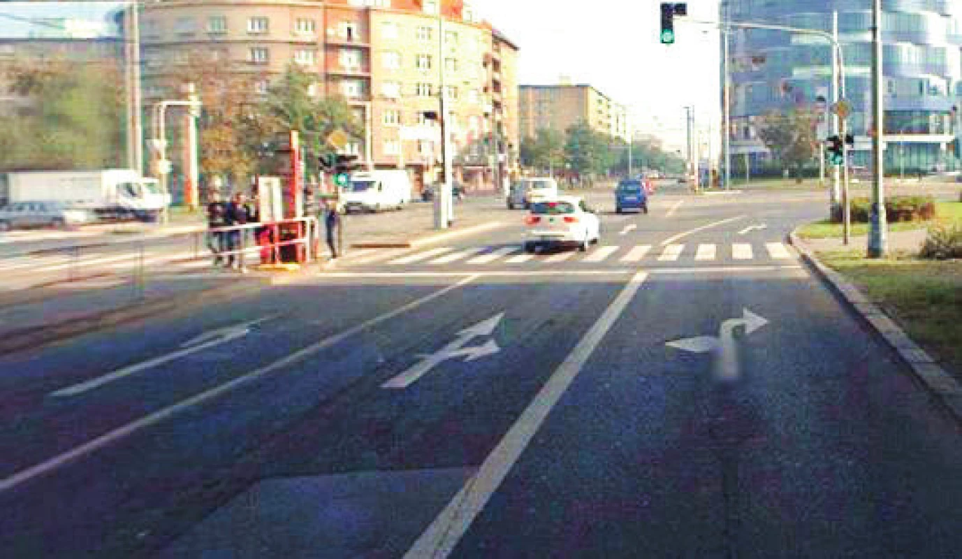 Snímek je z pozdější doby, kdy zmíněný chodník na pravé straně je nahrazen třetím řadicím pruhem pro odbočení vpravo